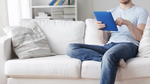 Man Relaxing on Couch Using Tablet Device