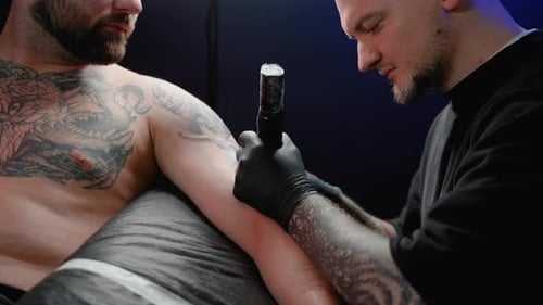 Professional Tattoo Artist Makes a Tattoo in the Studio Closeup