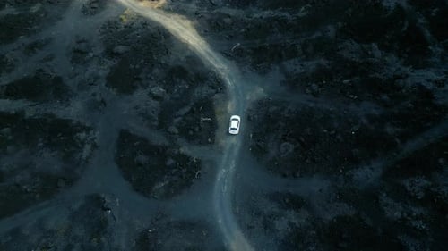 Vista aérea desde arriba del desierto volcánico negro en la naturaleza con una expedición de viaje en vehículo SUV en coche