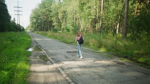 Back View Tourist Walking On Pothole Road With Head Down Under Power Lines