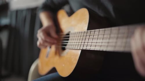 Close-up of hands strumming an acoustic guitar, creating a calm and creative atmosphere