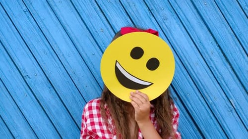 Girl Hides Behind Smiling Face Sign