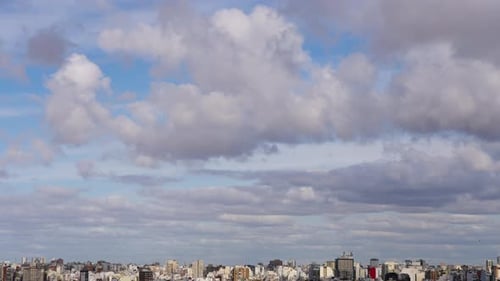 Cityscape below fluffy white clouds time lapse
