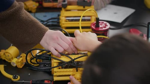 Unbekannter Lehrer hilft kleinem Schüler beim Bau eines Roboters