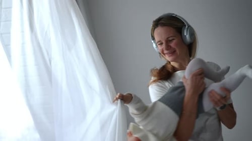 Mother Holds Baby Playfully Near Window