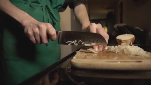 Hands Dicing Onion on Cutting Board in Kitchen