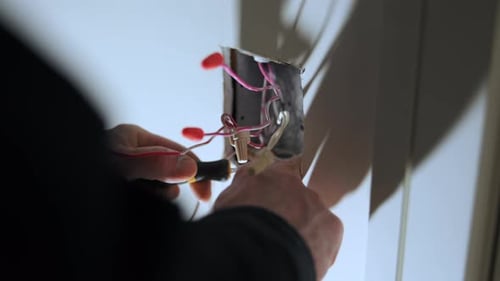 Close Up View of Hands Working with Electrical Wires and Outlet Box During Home Repair Installation