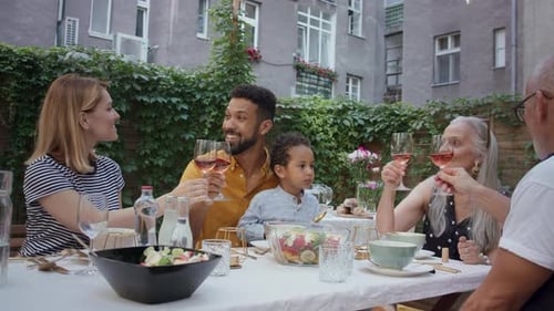 Family cheers together outdoors at celebratory meal