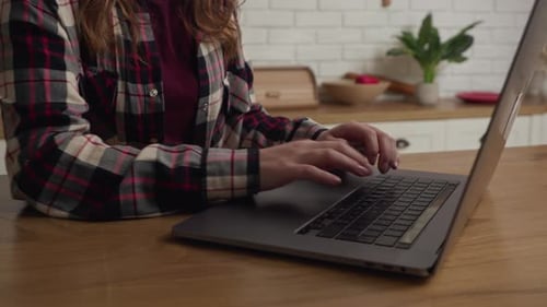 Woman Typing on Laptop at Kitchen Table