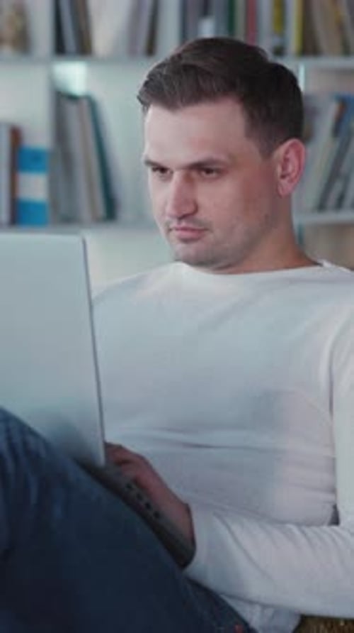 Man Using Laptop Answers Mobile Phone Call