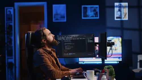 IT-Administrator denkt nach und trinkt Kaffee, während er früh am Morgen am PC arbeitet