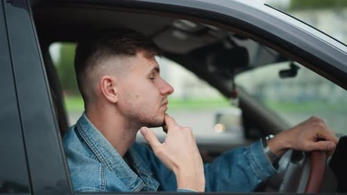 Pensive Young Man Sits in Driver's Seat