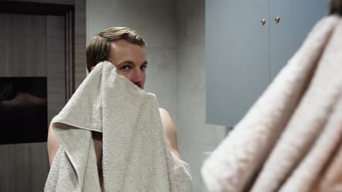Man Drying Face with Towel in Modern Bathroom