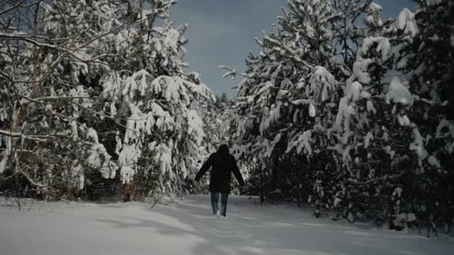 Happy young man walking in winter pine forest