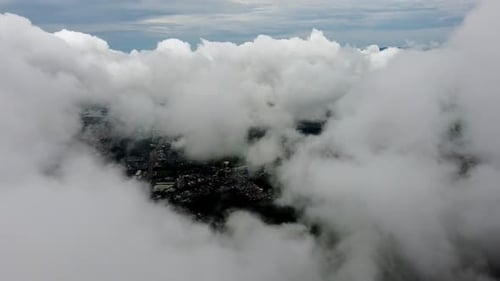 Cityscape Aerial View Through Fluffy White Clouds