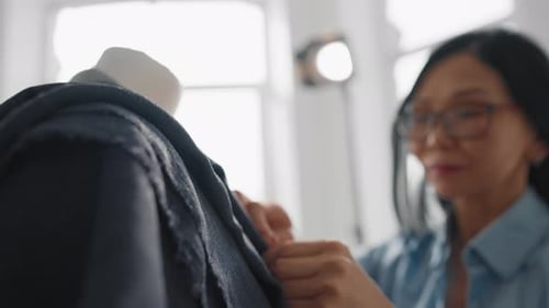 Woman Adjusting Garment on Mannequin