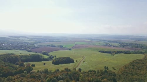 Flight over the forest and meadows with a view of the agricultural landscape in the background.