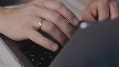 Male Hands Typing on Laptop Keyboard Close Up with Blurred Foreground