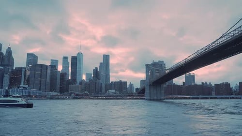 Brooklyn bridge with New York skyline at sunset in the background.