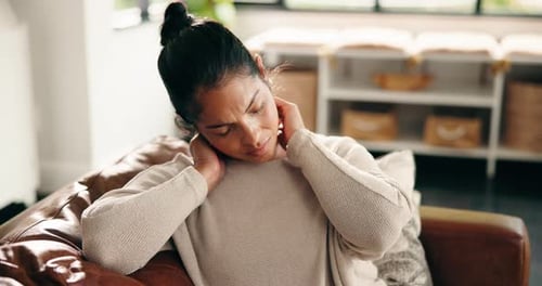 Woman Massaging Stiff Neck in Living Room