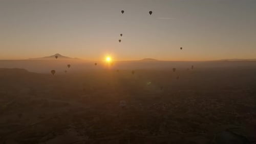 Drone view of hundreds of colorful hot air balloons soaring at sunrise in Cappadocia