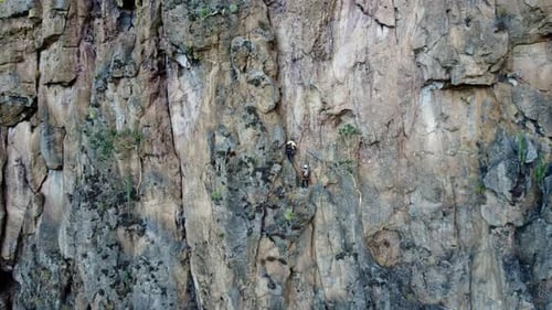 People Climbing a Rock Cliff Face with Ropes
