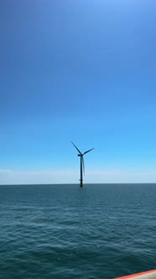 A Majestic Offshore Wind Turbine Stands Tall Against a Beautifully Clear Blue Sky Creating a
