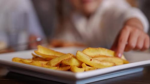 Child Takes a Fry from a Plate of Fries