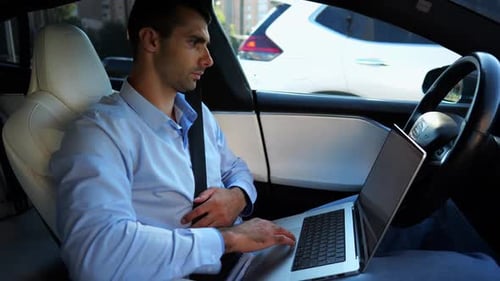 Handsome Entrepreneur Working on Notebook While Riding an Autonomous Self Driving Electric Car at