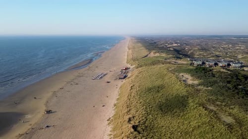 A beautiful aerial view of a sandy beach with rows of beach huts, people relaxing by the shore