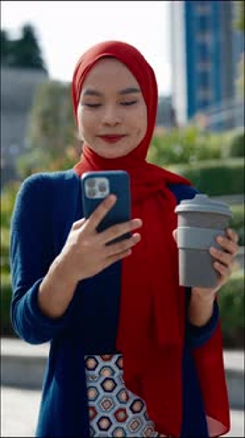 Portrait of Happy Muslim Woman with Coffee Cup Holding Smartphone on Street