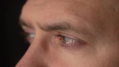 Man Eyes with Blinking Eyelids Close Up Male Face with Natural Skin on Black Background