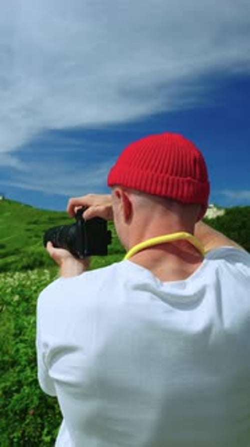 Man with Camera Taking Pictures in Green Field