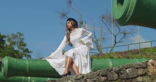 A young girl in a delicate, vintage wedding gown seated on the steps of a fortress.