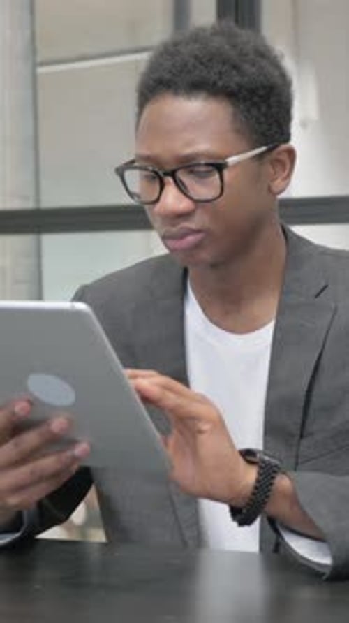 Vertical, Young African Man Using Digital Tablet in Office