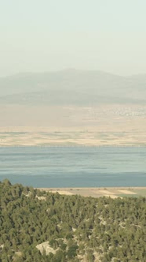 Vidéo verticale. En voiture, en haut des montagnes, vue sur un vaste lac derrière les montagnes.