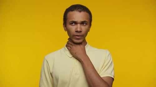 Young Man Feeling Throat Pain on Yellow Background