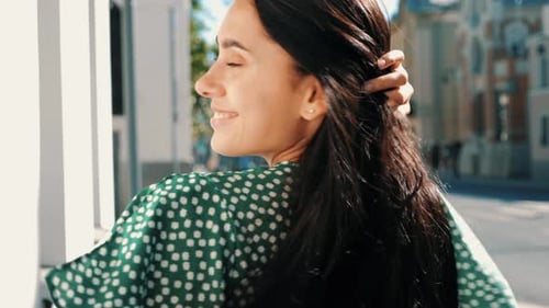 Smiling Woman Walking Down Urban Street, Glancing Back