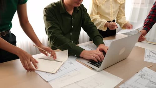 Architect compare writing detail of blueprint with plan in laptop. Delineation.