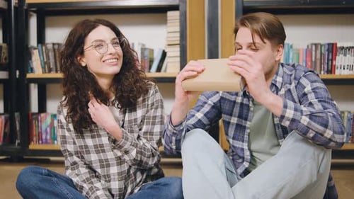 Enjoying a Cozy Moment Together While Students Reading a Book in a Library Setting with Shelves Full