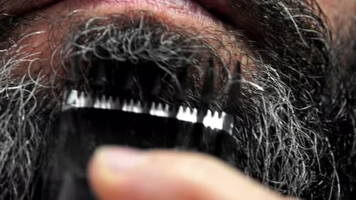 Man Trims Beard with Rechargeable Trimmer Close Up