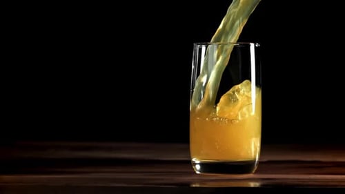 Orange Juice Pouring into Glass on Dark Wood