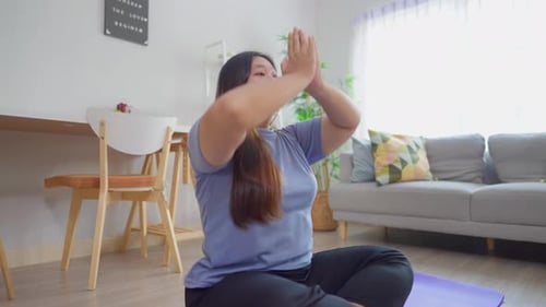 Asian plus-size woman exercising to lose weight in living room at home.