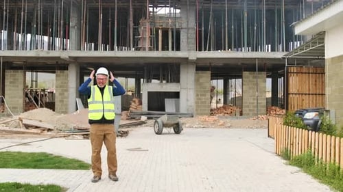 Fired construction worker angrily takes off his safety helmet and throws it on the ground