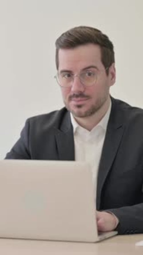 Man in Suit Gives Thumbs Up at Computer