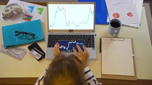 Woman following the stock market from phone and computer.