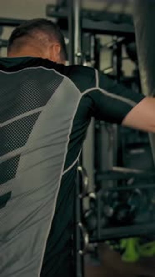 Vertical of Strong Sporty Athlete Hitting Punching Bag Indoor of Gym
