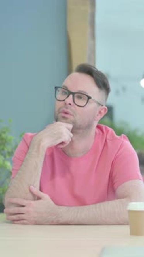 Man Sitting Thinking at a Desk with Coffee