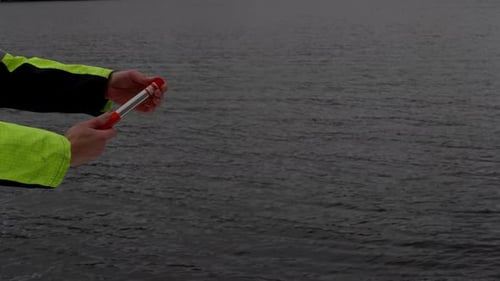 Crewmember in emergency launch maritime distress flare at sea, close up