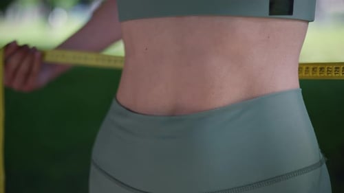 Adult Woman Measures Waist with Tape Measure